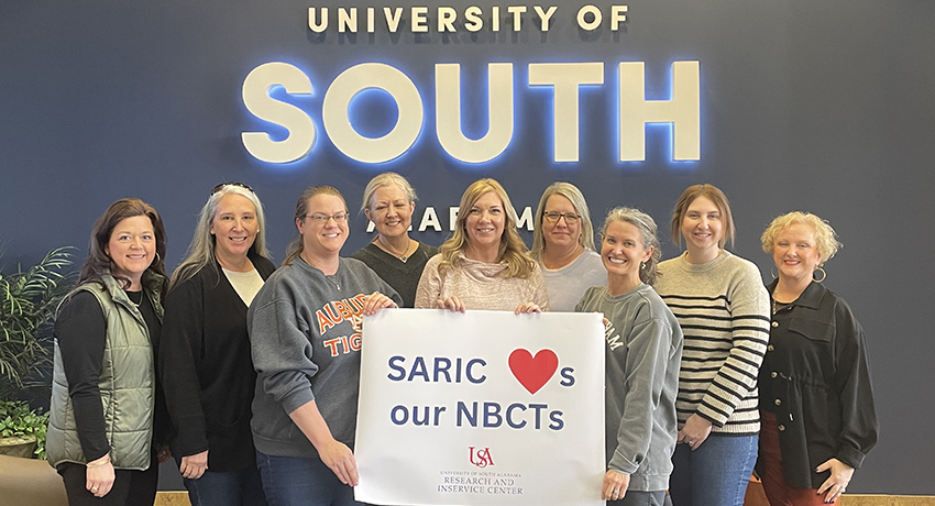 Nine current NBCTs holding a sign that reads SARIC heart emoji s our NBCTs with the SARIC logo below the words 