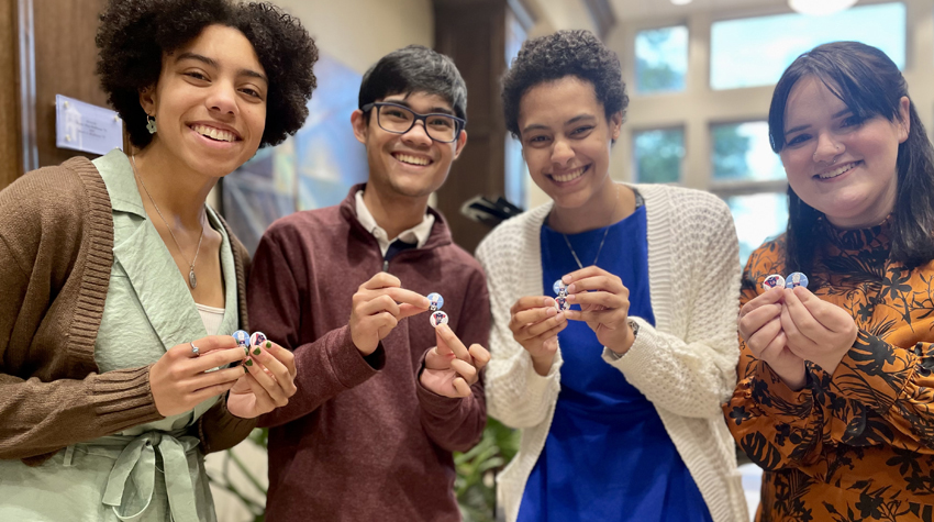 Four students holding buttons given to them by President Bonner.